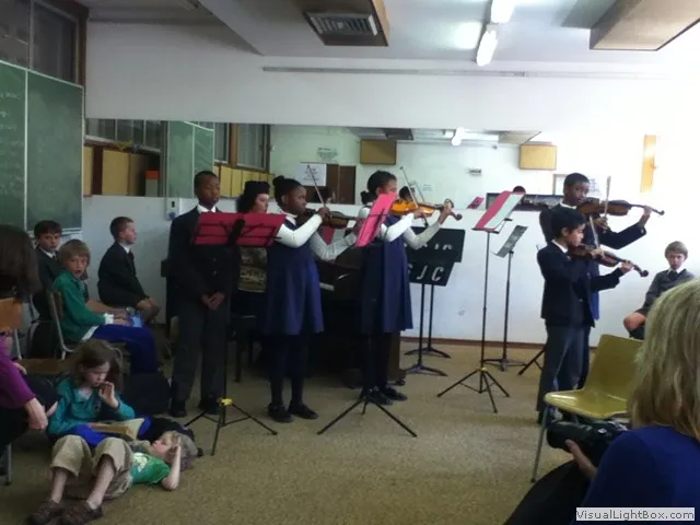 Young violin ensemble performing in classroom