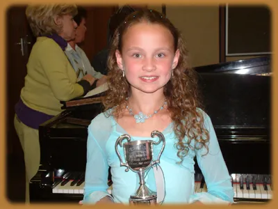 Young winner with trophy at piano